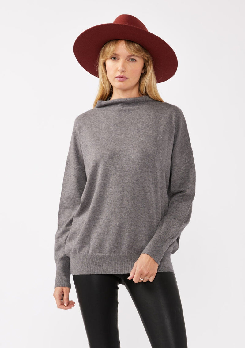 [Color: Heather Charcoal] A blonde model wearing a grey cozy lightweight pullover with a mock neckline. Complete with long sleeves, dropped shoulders, and a snugged ribbed trim. Perfect for layering or styling on its own for a relaxed, laid-back fall look. 