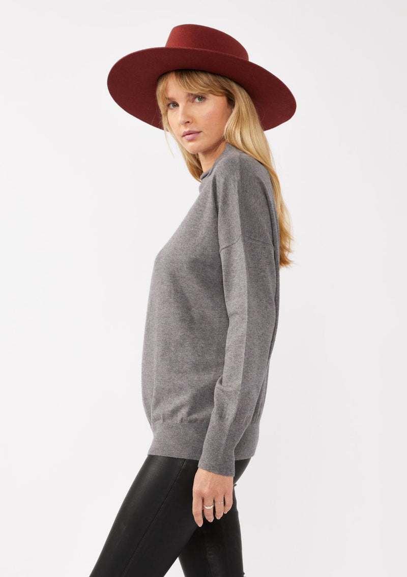 [Color: Heather Charcoal] A blonde model wearing a grey cozy lightweight pullover with a mock neckline. Complete with long sleeves, dropped shoulders, and a snugged ribbed trim. Perfect for layering or styling on its own for a relaxed, laid-back fall look. 