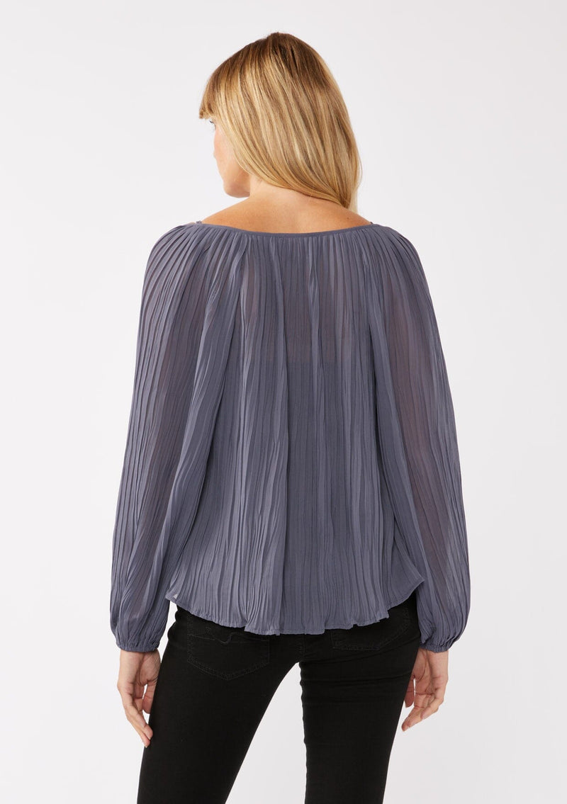 [Color: Slate Blue] A back facing image of a blonde model wearing a blue pleated chiffon blouse. Featuring a split v-neckline with tie detail, long sleeves, and elastic cuffs. A flowy, relaxed top for the office or special occasions. 