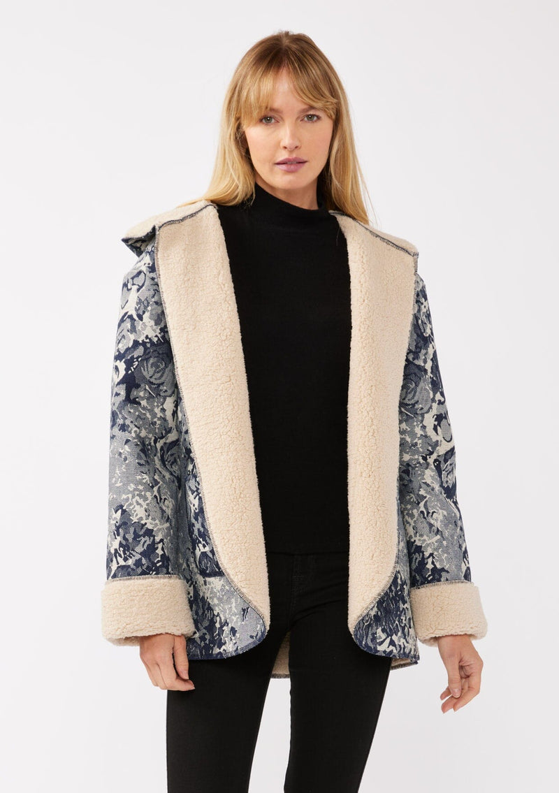 [Color: Denim Blue] A front-facing image of a blonde model wearing a denim floral jacket with a sherpa lining. The jacket features a cozy shawl collar, open front, patch pockets, long sleeves, and fold-over cuffs with exposed sherpa.