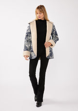 [Color: Denim Blue] A front-facing image of a blonde model wearing a denim floral jacket with a sherpa lining. The jacket features a cozy shawl collar, open front, patch pockets, long sleeves, and fold-over cuffs with exposed sherpa.