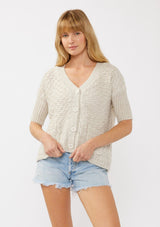 [Color: Bone] A front-facing image of a blonde model wearing a cozy, cropped knit cardigan with a V-neckline, button front, and ribbed half sleeves. Ideal for lounging or layering for a relaxed, casual style.