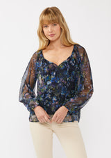 [Color: Black/Dusty Pink] A front facing image of a blonde model in a navy sheer micro mesh blouse with floral print, featuring long sleeves, tie-front detail, elastic cuffs, and cami lining; perfect for evening and casual chic styling.