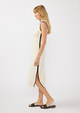 [Color: Natural/Black] A side facing image of a blonde model wearing an off white tank midi dress crafted in a stripe knit texture with a round neckline, side slits, and a black contrast stitch trim. A casual throw-on for vacation, resort styling, and lounging. 