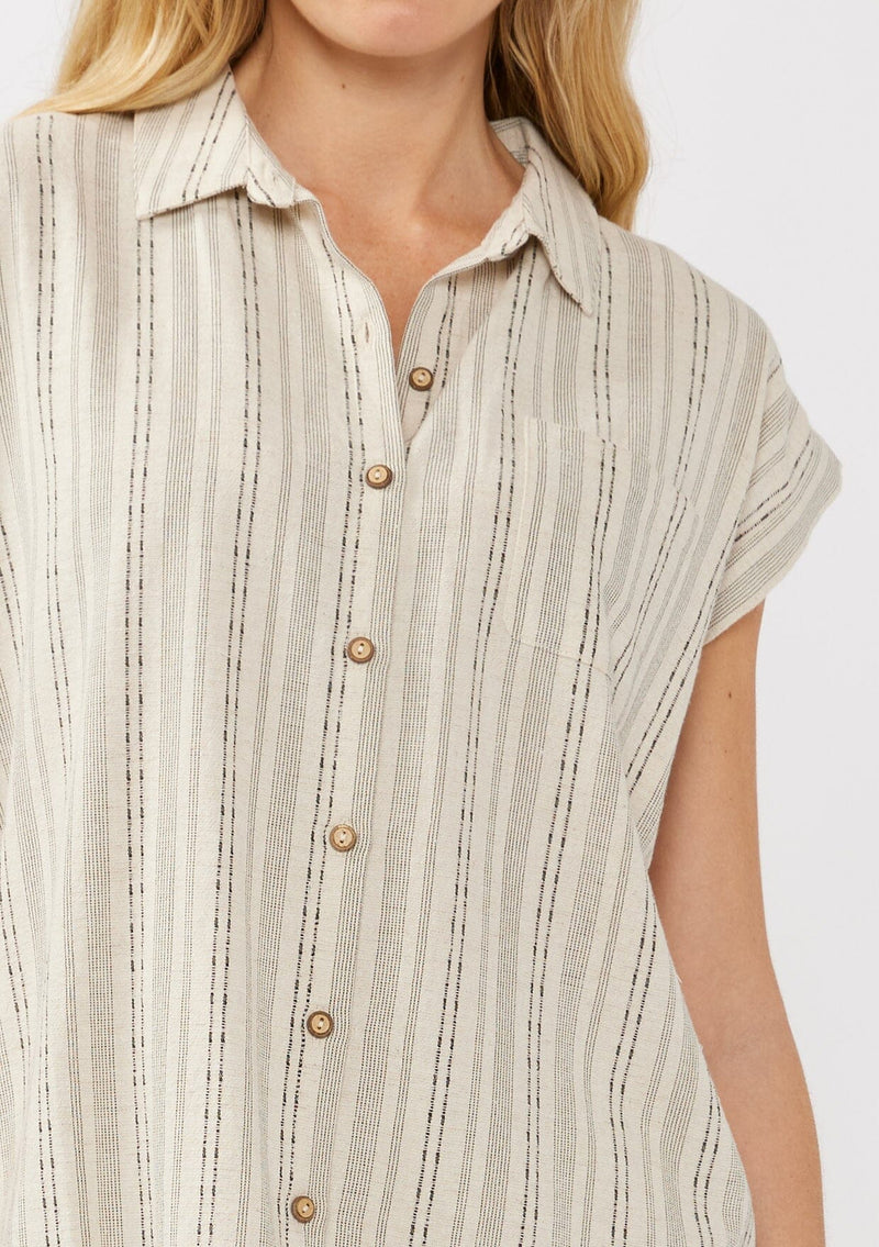 [Color: Natural/Black] A detail image of a blonde model wearing a beige camp shirt in a cotton blend with a black yarn-dye stripe pattern, featuring a collared neckline, short dolman sleeves, and button-front closure—ideal for lounging, vacation days, or resort styling.