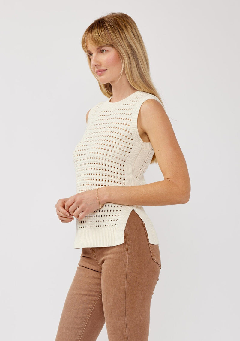 [Color: Ivory] A side facing image of a blonde model wearing an ivory sleeveless open knit sweater vest with a crew neckline, ribbed trim, and side slits. Perfect for layering over long sleeves or wearing on its own. 