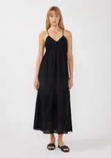 [Color: Black] A front image of a blonde model wearing a bohemian-inspired black maxi dress featuring embroidered eyelet details and textured clip dots. The relaxed, tiered silhouette includes adjustable straps, a v-neckline, and a racerback design, making it ideal for beach days, weddings, or any special occasion.