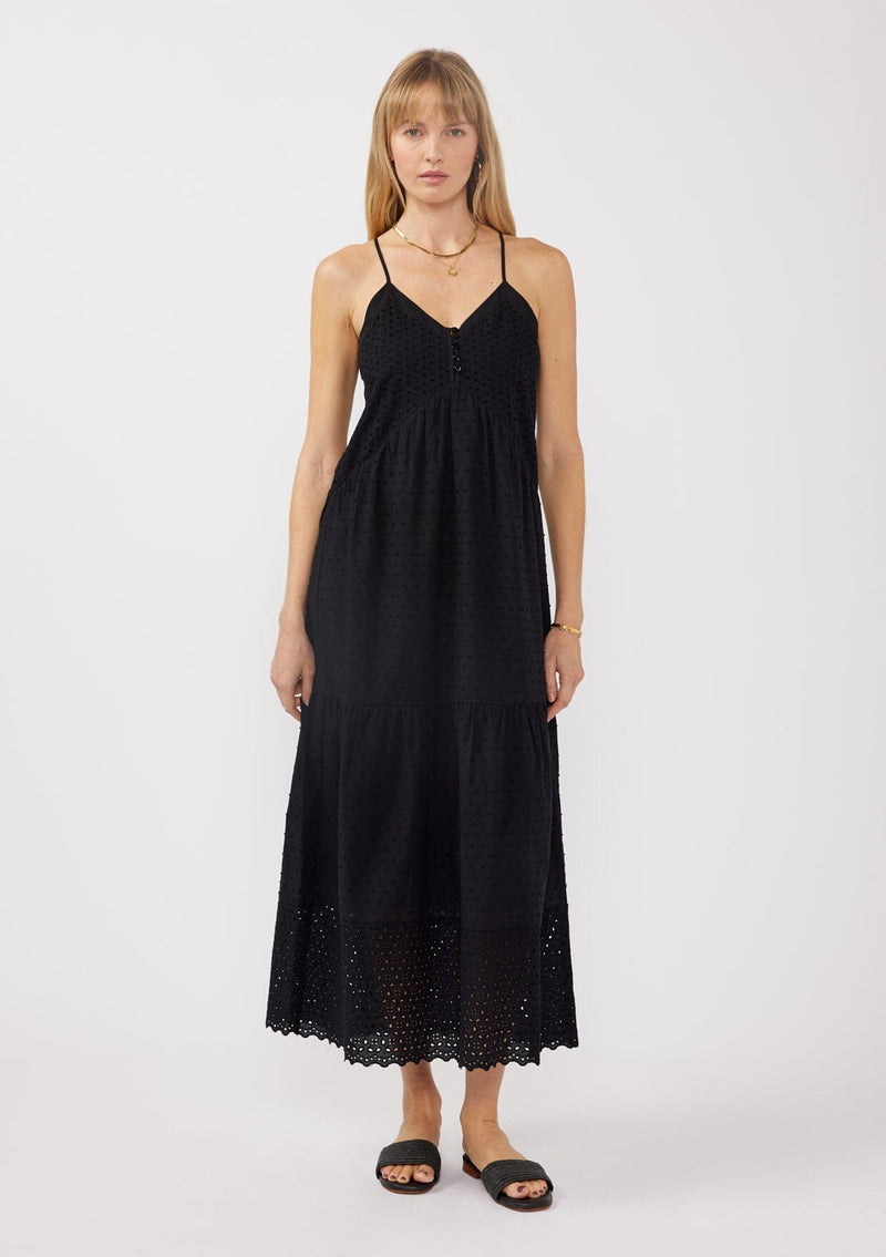 [Color: Black] A front image of a blonde model wearing a bohemian-inspired black maxi dress featuring embroidered eyelet details and textured clip dots. The relaxed, tiered silhouette includes adjustable straps, a v-neckline, and a racerback design, making it ideal for beach days, weddings, or any special occasion.