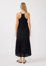 [Color: Black] A back image of a blonde model wearing a bohemian-inspired black maxi dress featuring embroidered eyelet details and textured clip dots. The relaxed, tiered silhouette includes adjustable straps, a v-neckline, and a racerback design, making it ideal for beach days, weddings, or any special occasion.