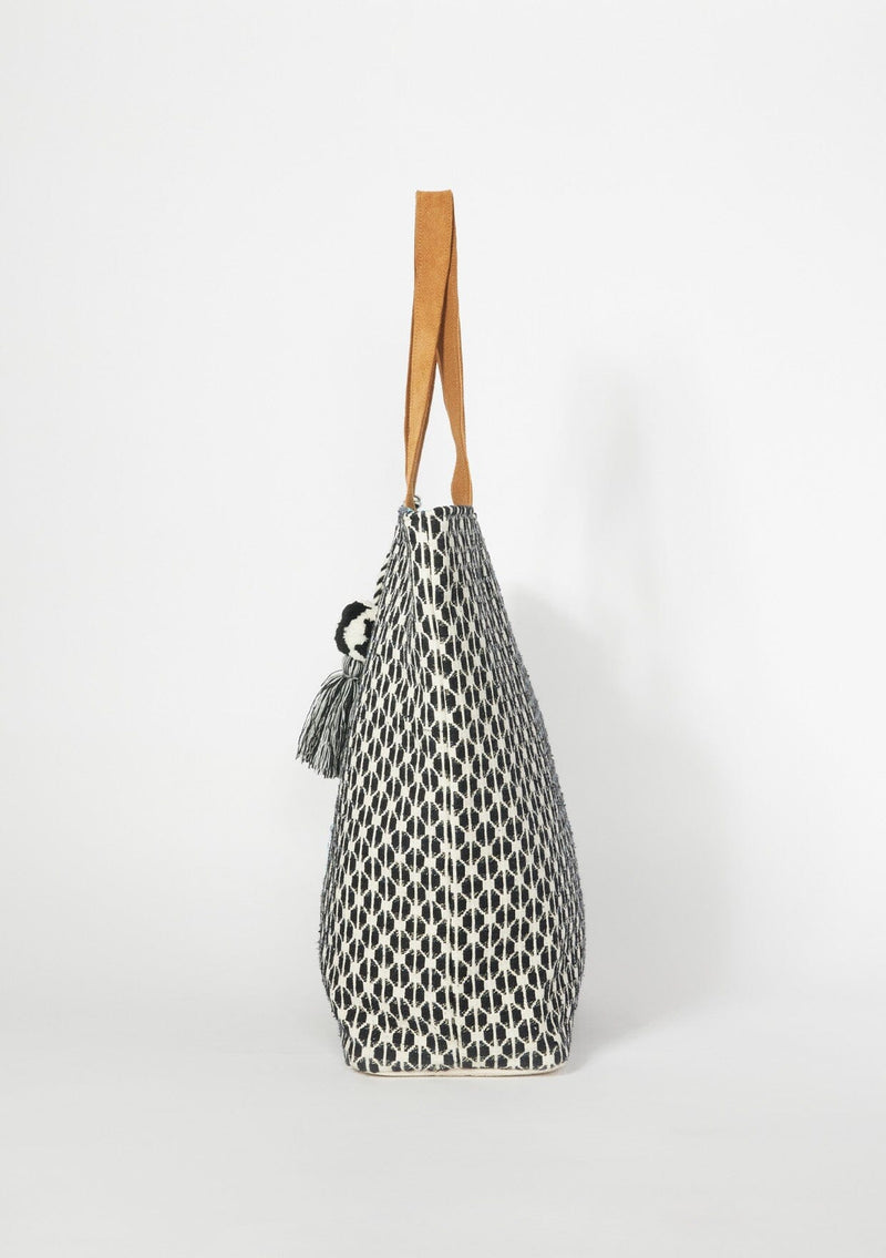 [Color: Black/Blue] An oversized bohemian tote bag with a black patterned exterior and contrast blue interior. With gold metallic lurex thread details, a sequined hand motif, an oversized tassel accent, two suede top handles, and a magnetic snap closure. 