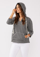 [Color: Black] A brunette model wearing a striped hoodie pullover in black with white stripes. Featuring 3/4 length sleeves, v-neckline, and a kangaroo pocket. A casual beach throw on that can be worn over a swimsuit or ripped denim cut offs. 