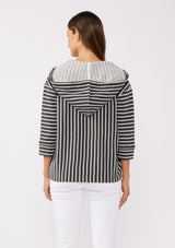 [Color: Black] A brunette model wearing a striped hoodie pullover in black with white stripes. Featuring 3/4 length sleeves, v-neckline, and a kangaroo pocket. A casual beach throw on that can be worn over a swimsuit or ripped denim cut offs. 