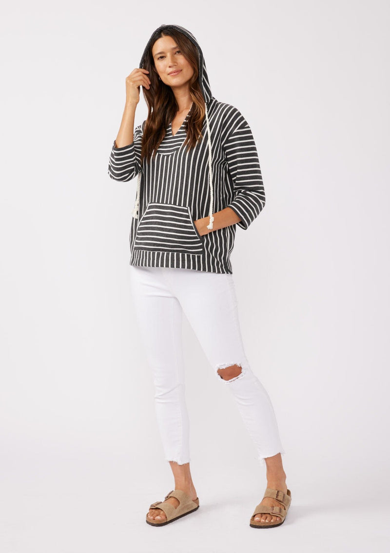 [Color: Black] A brunette model wearing a striped hoodie pullover in black with white stripes. Featuring 3/4 length sleeves, v-neckline, and a kangaroo pocket. A casual beach throw on that can be worn over a swimsuit or ripped denim cut offs. 