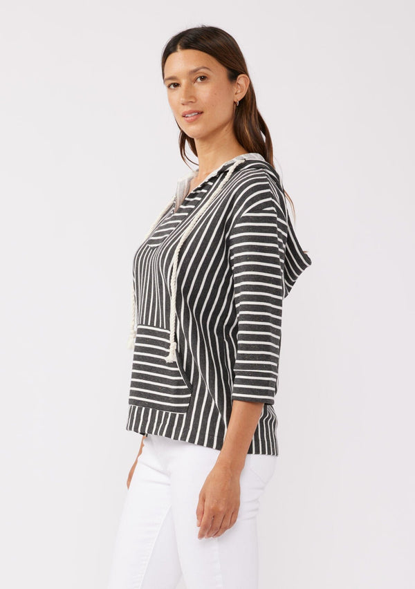 [Color: Black] A brunette model wearing a striped hoodie pullover in black with white stripes. Featuring 3/4 length sleeves, v-neckline, and a kangaroo pocket. A casual beach throw on that can be worn over a swimsuit or ripped denim cut offs. 