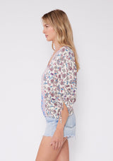 [Color: Natural/Magenta] Blonde woman wearing a bohemian mixed floral print top. A standout summer blouse with a flattering v-neckline, button front, and 3/4 length ruched sleeves, and an elastic hem for added comfort. The perfect Summer top to pair with denim.