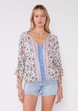[Color: Natural/Magenta] Blonde woman wearing a bohemian mixed floral print top. A standout summer blouse with a flattering v-neckline, button front, and 3/4 length ruched sleeves, and an elastic hem for added comfort. The perfect Summer top to pair with denim.