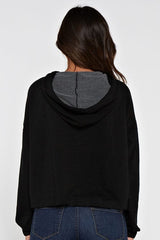 [Color: Black]  A brunette model wearing a solid black pullover hoodie with a drawstring hood, long sleeves, and dropped shoulders. The cropped length makes it perfect for lounging, travel, or casual fall outings.