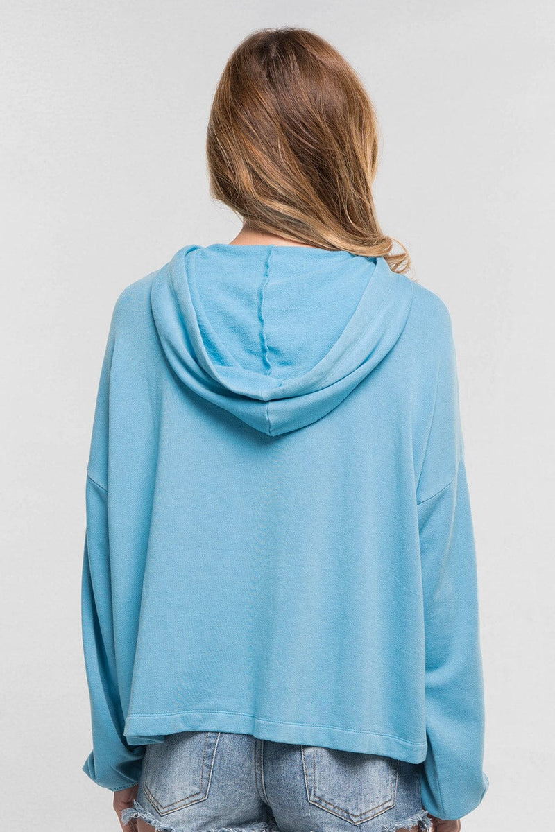 [Color: Cool Blue]  A blonde model wearing a solid blue pullover hoodie with a drawstring hood, long sleeves, and dropped shoulders. The cropped length makes it perfect for lounging, travel, or casual fall outings.