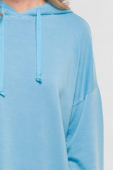 [Color: Cool Blue]  A blonde model wearing a solid blue pullover hoodie with a drawstring hood, long sleeves, and dropped shoulders. The cropped length makes it perfect for lounging, travel, or casual fall outings.