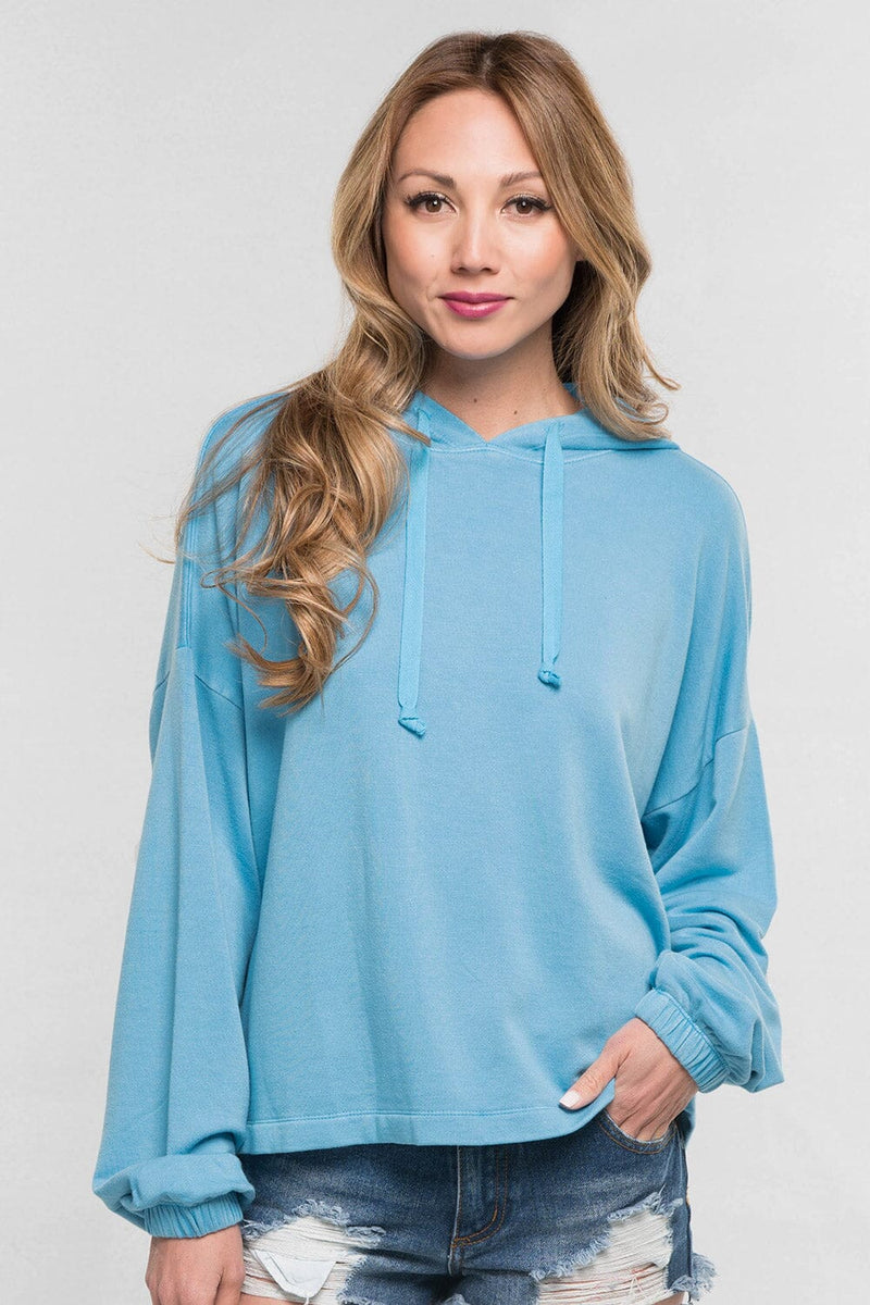 [Color: Cool Blue]  A blonde model wearing a solid blue pullover hoodie with a drawstring hood, long sleeves, and dropped shoulders. The cropped length makes it perfect for lounging, travel, or casual fall outings.