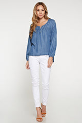 [Color: Vintage Wash] An asian model wearing a tencel blue denim blouse with a button front, yoke, long sleeves with dropped shoulders, and elastic wrist cuffs. 