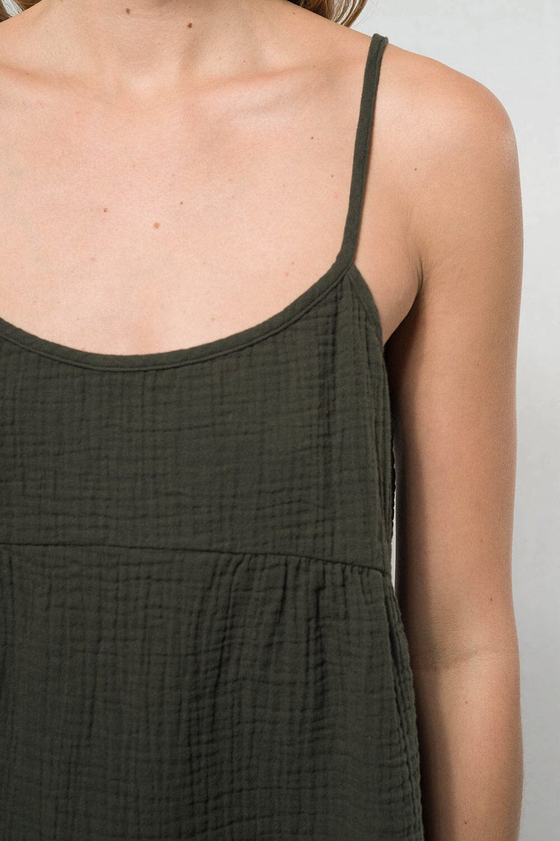 [Color: Evergreen] A blonde model wearing a forest green lightweight, cotton gauze tank top with skinny adjustable straps, a scoop neckline, and a relaxed fit. 