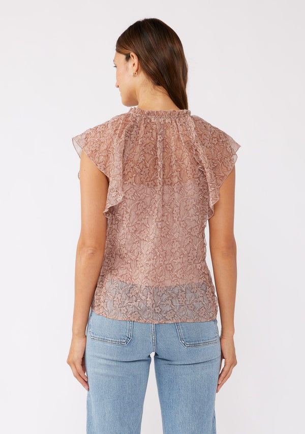 [Color: Mauve] A back image of a brunette model wearing a crinkled chiffon top with a floral pattern. This rose taupe top features a sheer flowy silhouette, flutter short sleeves, split v neckline with ties, and a ruffled details with a merrow edge finish.  