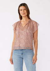 [Color: Mauve] A brunette model wearing a crinkled chiffon top with a floral pattern. This rose taupe top features a sheer flowy silhouette, flutter short sleeves, split v neckline with ties, and a ruffled details with a merrow edge finish.  