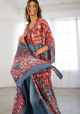 [Color: Blue/Brick] A model wearing a red and blue bohemian mid length kimono. Featuring half length kimono sleeves, side slits, an open front, and a multi colored bohemian pattern throughout.