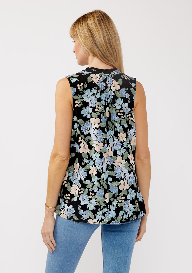 [Color: Black/Pale Blue] A back facing image of a blonde model wearing a black and blue floral print blouse sleeveless top. Featuring a button front and a split v neckline with a ruffle trim detail. Perfect for work and special occasions. 