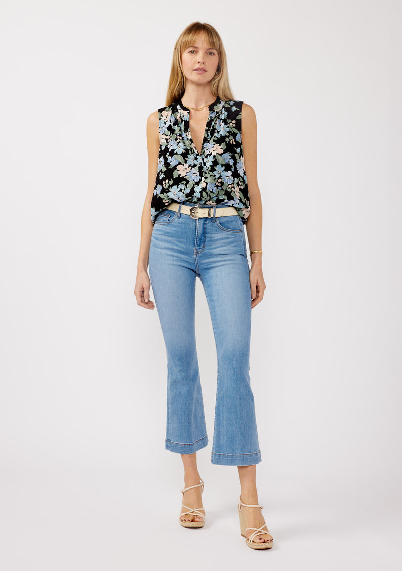 [Color: Black/Pale Blue] A front facing image of a blonde model wearing a black and blue floral print blouse sleeveless top. Featuring a button front and a split v neckline with a ruffle trim detail. Perfect for work and special occasions. 