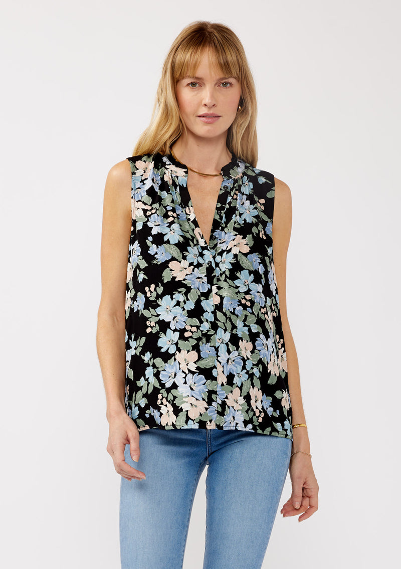 [Color: Black/Pale Blue] A front facing image of a blonde model wearing a black and blue floral print blouse sleeveless top. Featuring a button front and a split v neckline with a ruffle trim detail. Perfect for work and special occasions. 