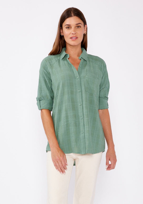 [Color: Dusty Olive] Brunette woman wearing an olive green plaid seersucker shirt with a button front, roll tab long sleeve, collared neckline. A great top to pair with denim  pants or shorts. 