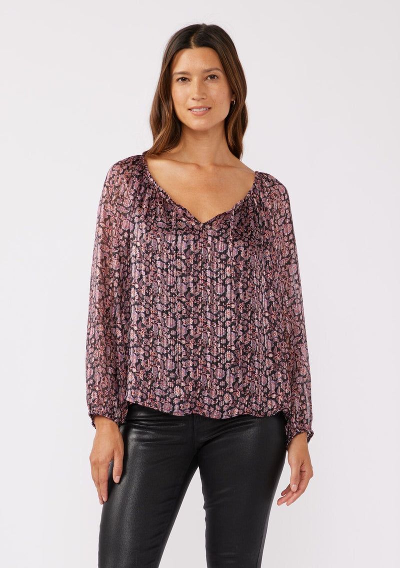 [Color: Black/Plum] A front facing image of a brunette model wearing sheer lurex stripe top with a standout purple floral print. This holiday blouse features long sleeves, elastic cuffs, and split v neckline with a tie front detail. Elegantly styled for the holiday season and special occasions. 