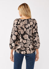 [Color: Black/Taupe] A back facing image of a blonde model wearing a black and taupe floral print blouse. This boho casual blouse features a self covered button front, a split v-neckline, and 3/4 length sleeves. Perfect for any casual outing or vacation. 