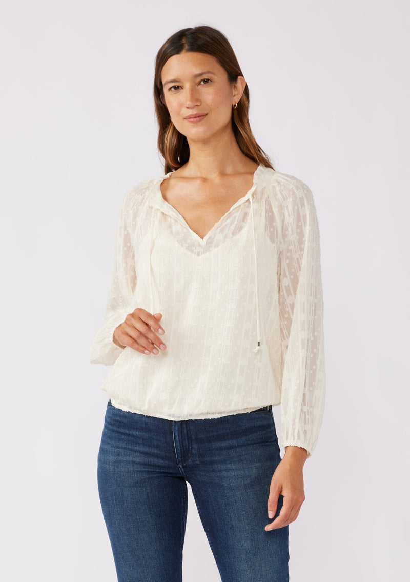 [Color: Ivory] A brunette model wearing a n ivory off white shimmer blouse crafted on textured chiffon. With a split v neckline with ties, long sleeves, and an elastic hem. The perfect special occasion blouse for formal events or holidays