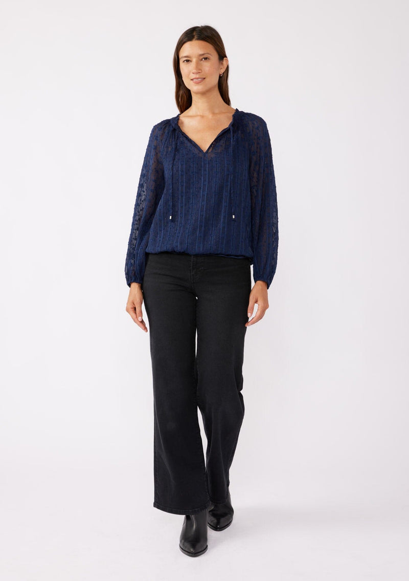 [Color: Navy] A brunette model wearing a navy shimmer blouse crafted on textured chiffon. With a split v neckline with ties, long sleeves, and an elastic hem. The perfect special occasion blouse for formal events or holidays.   