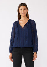 [Color: Navy] A brunette model wearing a navy shimmer blouse crafted on textured chiffon. With a split v neckline with ties, long sleeves, and an elastic hem. The perfect special occasion blouse for formal events or holidays.   