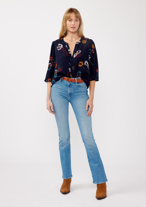 [Color: Navy/Mustard] A front facing image of a blonde model wearing a bohemian fall blouse in a blue floral print. With long sleeves, a v neckline, a self covered button front, and a relaxed fit. 