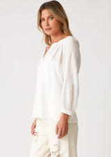 [Color: Black] A side facing image of a blonde model wearing a white bohemian blouse. With a v neckline, long sleeves, and embroidered detail.