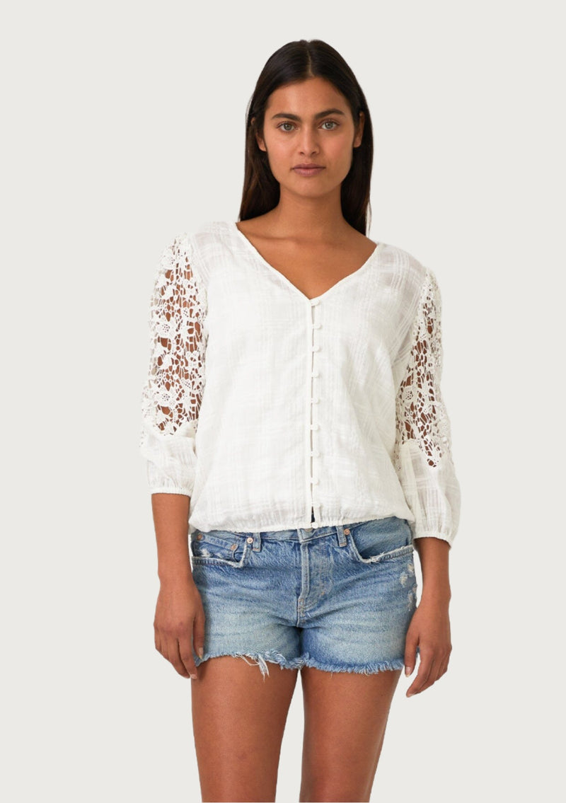 [Color: Off White] A front facing image of a brunette model wearing a white cotton bohemian blouse designed in a textured dobby plaid. With three quarter length crochet sleeves, a v neckline, a self covered button front, and an elastic waist. 
