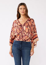 [Color: Wine/Dusty Rose] A front image of a brunette model wearing an orange and red bohemian floral border print blouse. Perfectly suited for the fall season, with flowy kimono sleeves, button front, flattering v neckline, and half smocked elastic waist at the back. A trendy and stylish boho top paired with vintage denim. 