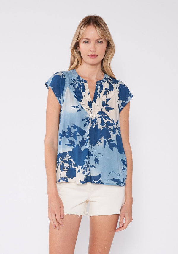 [Color: Navy/Dusty Blue] Bohemian summer top featuring short cap sleeves, a split v neckline, gathered details at the yoke, and a raw edge hem. The light blue and white tropical floral print gives endless summer vacation vibes.