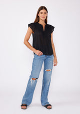 [Color: Black] A blond model wearing a black bohemian top crafted from lightweight cotton gauze. With short cap sleeves, a split v neckline, gathered details at the yoke, and a raw edge hem.