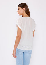 [Color: White] A brunette model wearing a white sheer top with a split v neckline and short dolman sleeves. A casual summer top with an embroidered eyelet detail at the hem with a 3 button front closure.