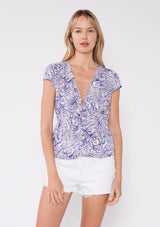 [Bone/Lilac] This top features a delicate floral and foliage print in shades of lilac on a bone-colored background. Made from lightweight fabric, it has a deep V-neckline with a small center keyhole detail, adding a hint of allure. The cap sleeves and gathered waistband create a flattering silhouette, making this top perfect for both casual and evening wear. Its nature-inspired charm is ideal for a spring or summer wardrobe.