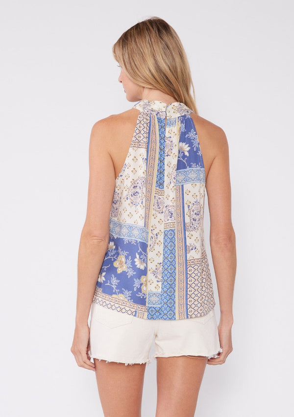 [Color: Ivory/Lilac] A back facing image of a blonde model wearing a sleeveless bohemian halter tank top in an ivory and lilac purple patchwork floral print. With a cross front halter neckline and a relaxed fit. 