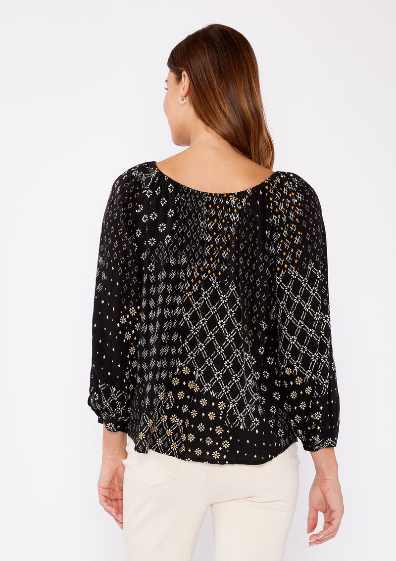 [Color: Black/Gold] A brunette woman wearing a black mixed floral print blouse with an elastic scoop neckline, long sleeves, and button cuff closures. A casual fall boho top perfect for any occasion.