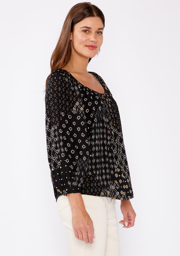 [Color: Black/Gold] A brunette woman wearing a black mixed floral print blouse with an elastic scoop neckline, long sleeves, and button cuff closures. A casual fall boho top perfect for any occasion.