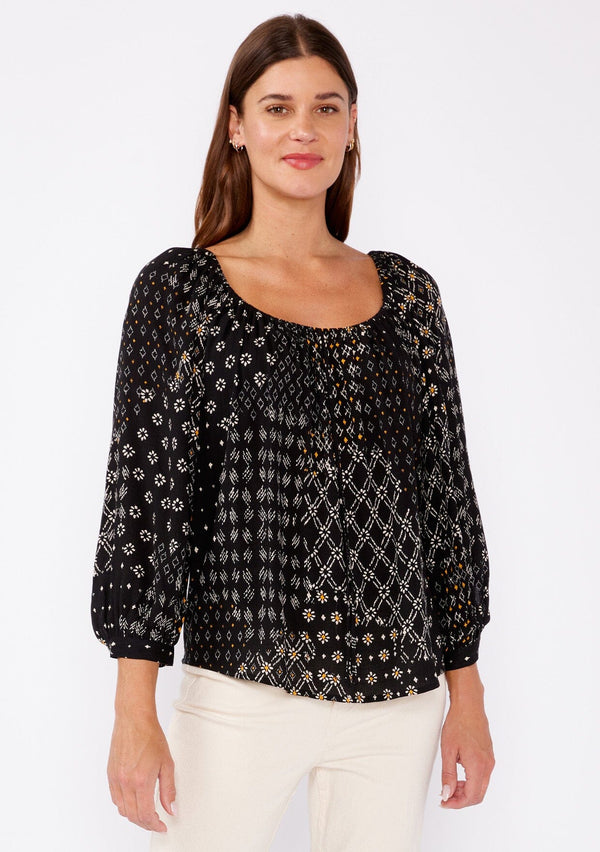 [Color: Black/Gold] A brunette woman wearing a black mixed floral print blouse with an elastic scoop neckline, long sleeves, and button cuff closures. A casual fall boho top perfect for any occasion. 